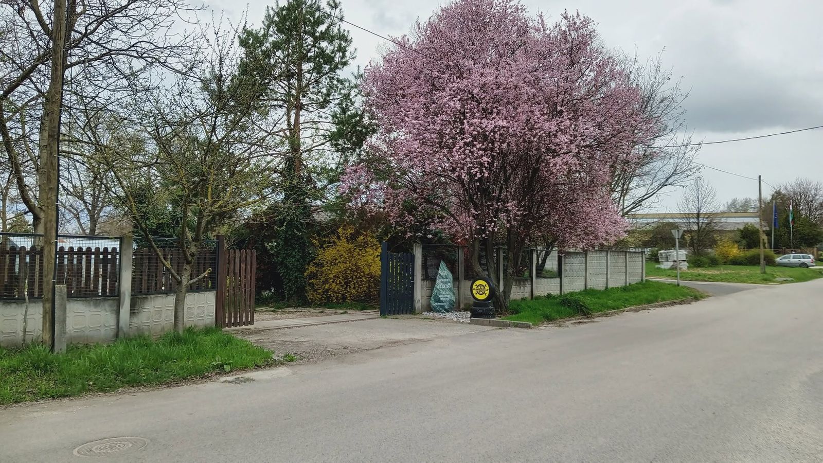 A gumiszerviz bejárata az utca felől, a kapu mellett sárga tábla